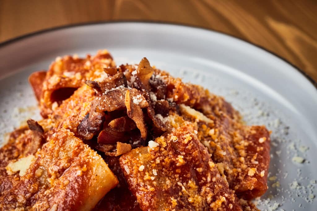 Soczysta lasagne z naleśników z mięsnymi pulpecikami na kremowym, porcelanowym talerzu.