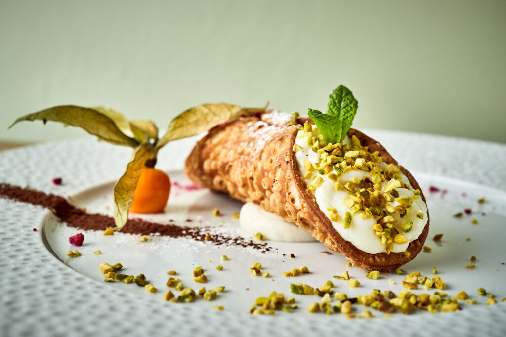 Prawdziwe włoskie Cannoli Siciliani podane z pokruszonymi pistacjami i świeżą miętą.